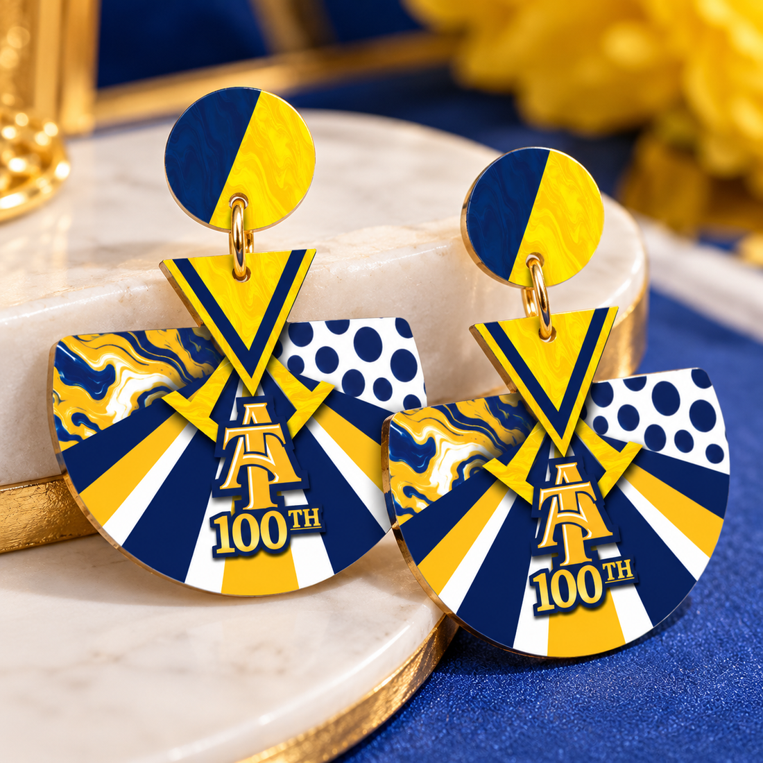 Sunburst acrylic earrings with navy, gold and white rays and a centennial 100th emblem
