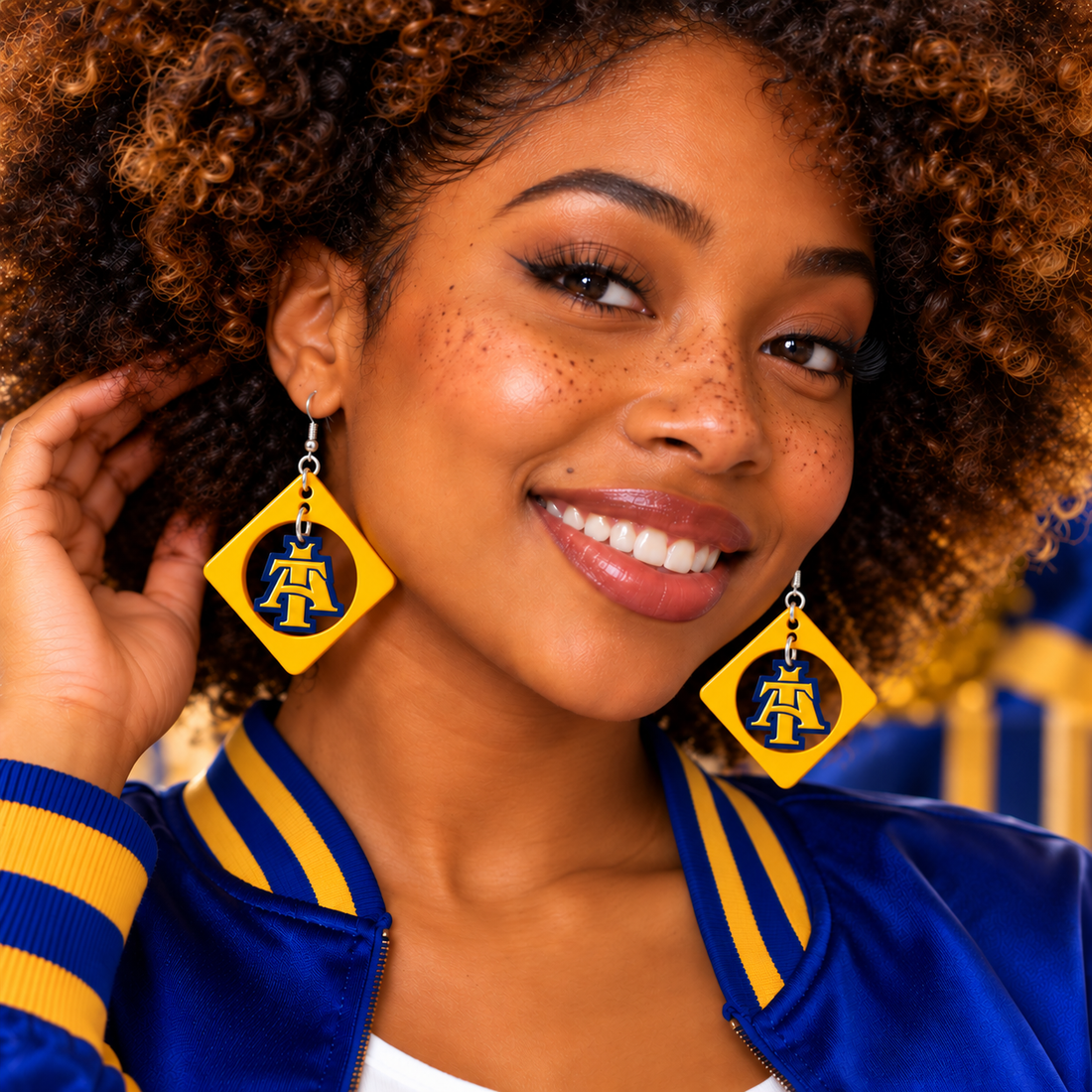 Gold frame diamond swing earrings worn by a smiling woman, gold and blue acrylic homecoming earrings